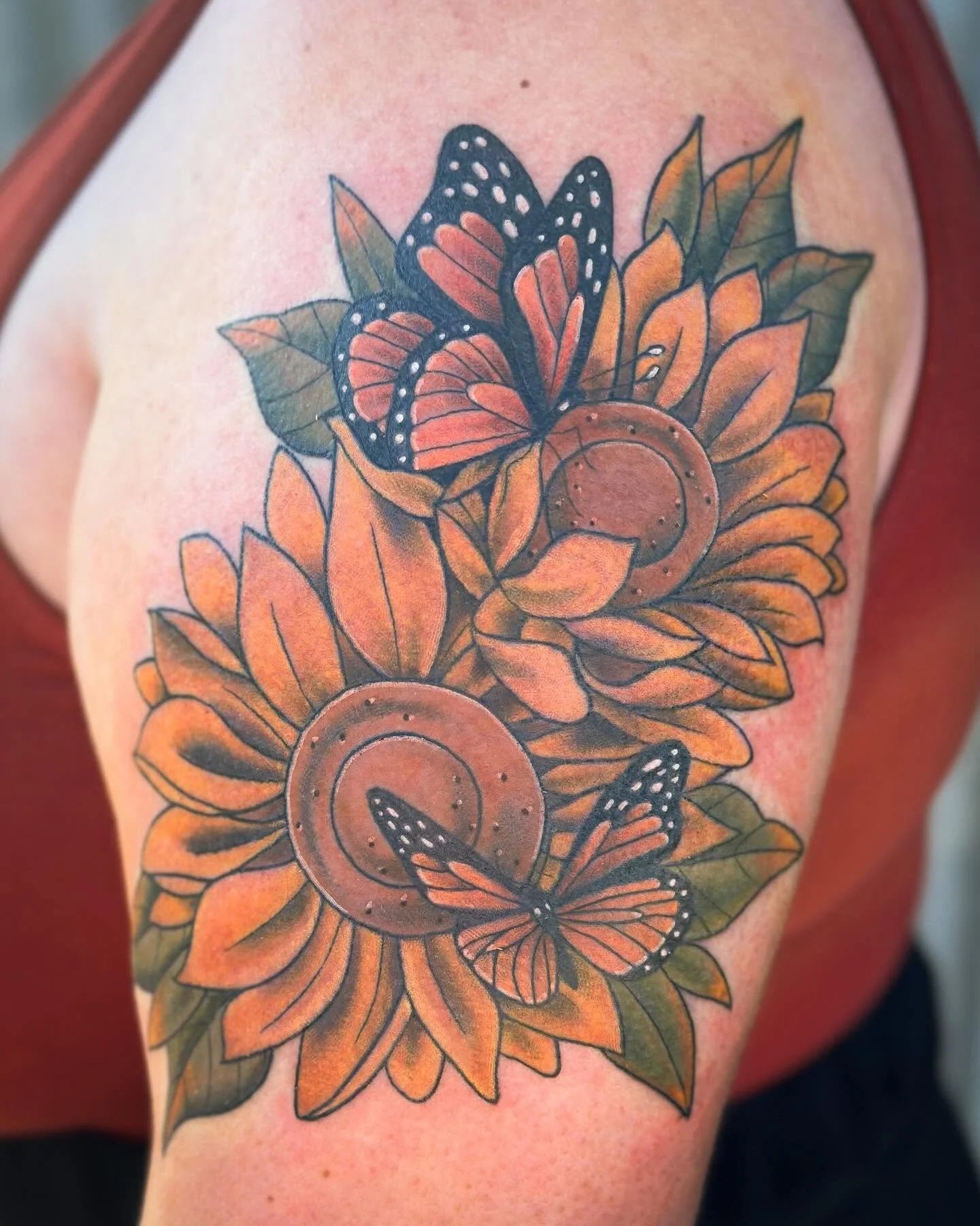 Tattoo of sunflowers and butterflies on a person's upper arm.