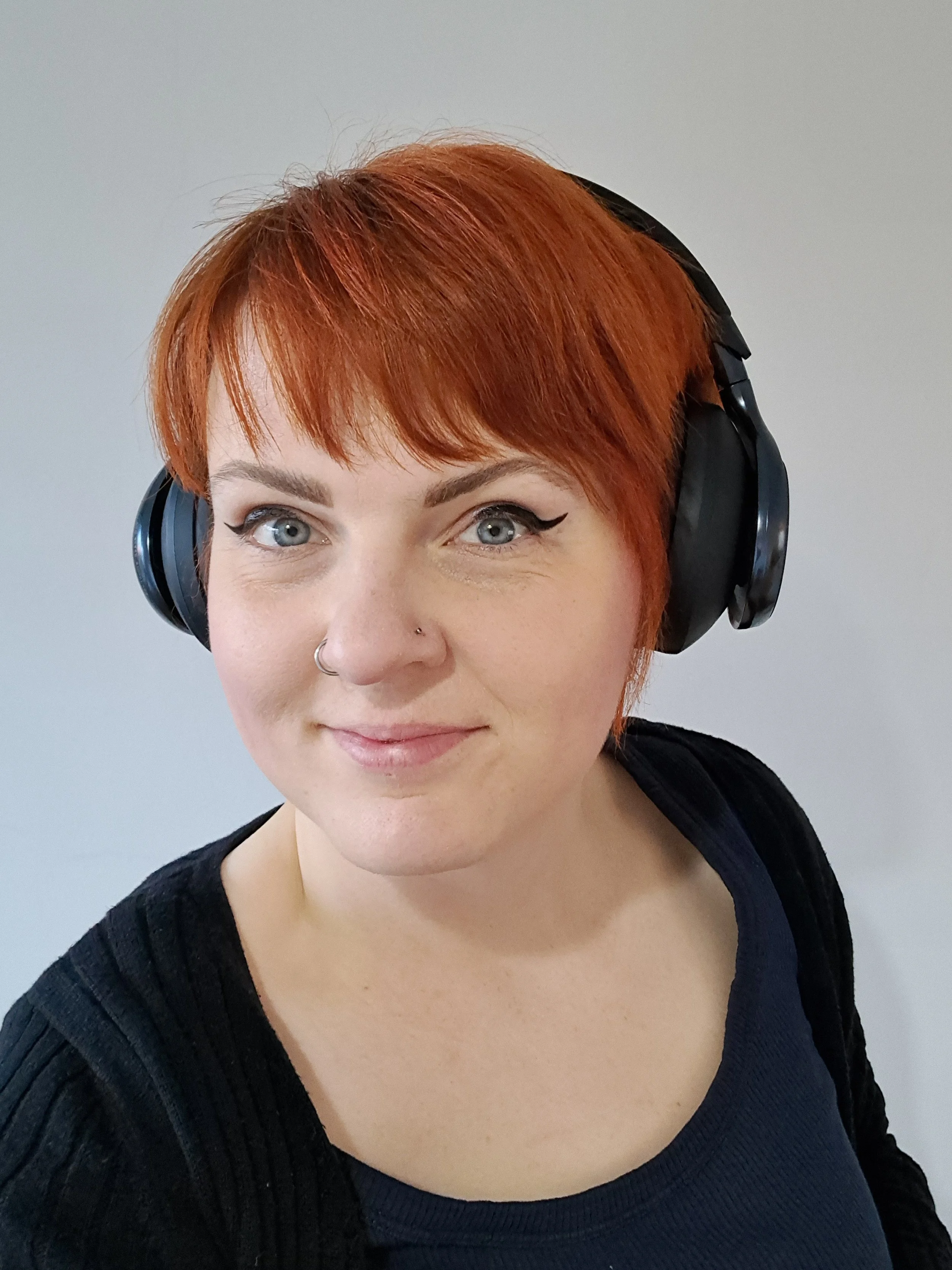 Kat is a creative virtual assistant with copper hair and black headphones smiling