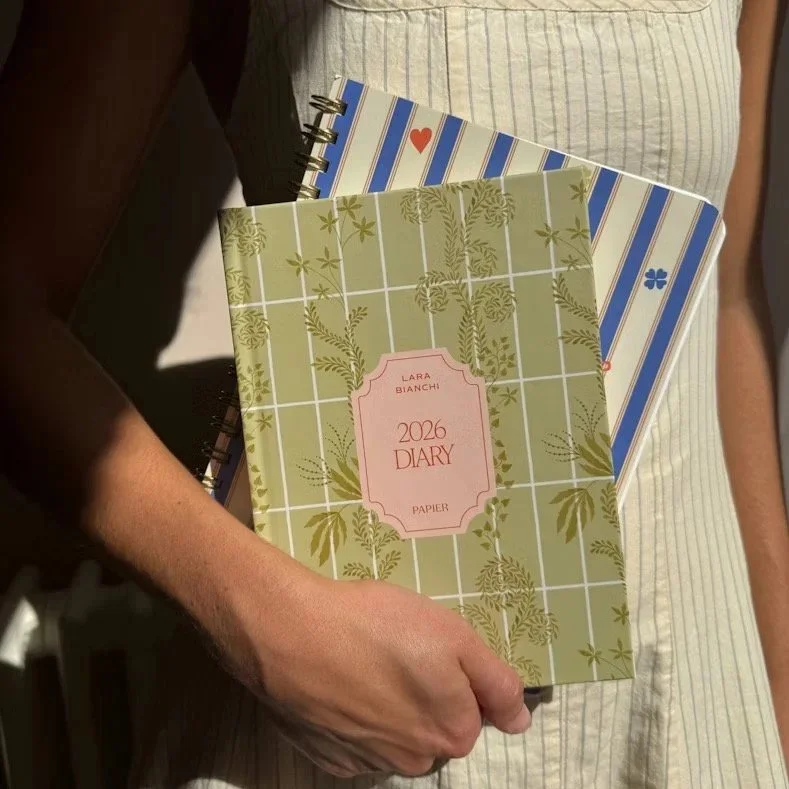 hand holding a 2026 diary and a spiral bound notebook.