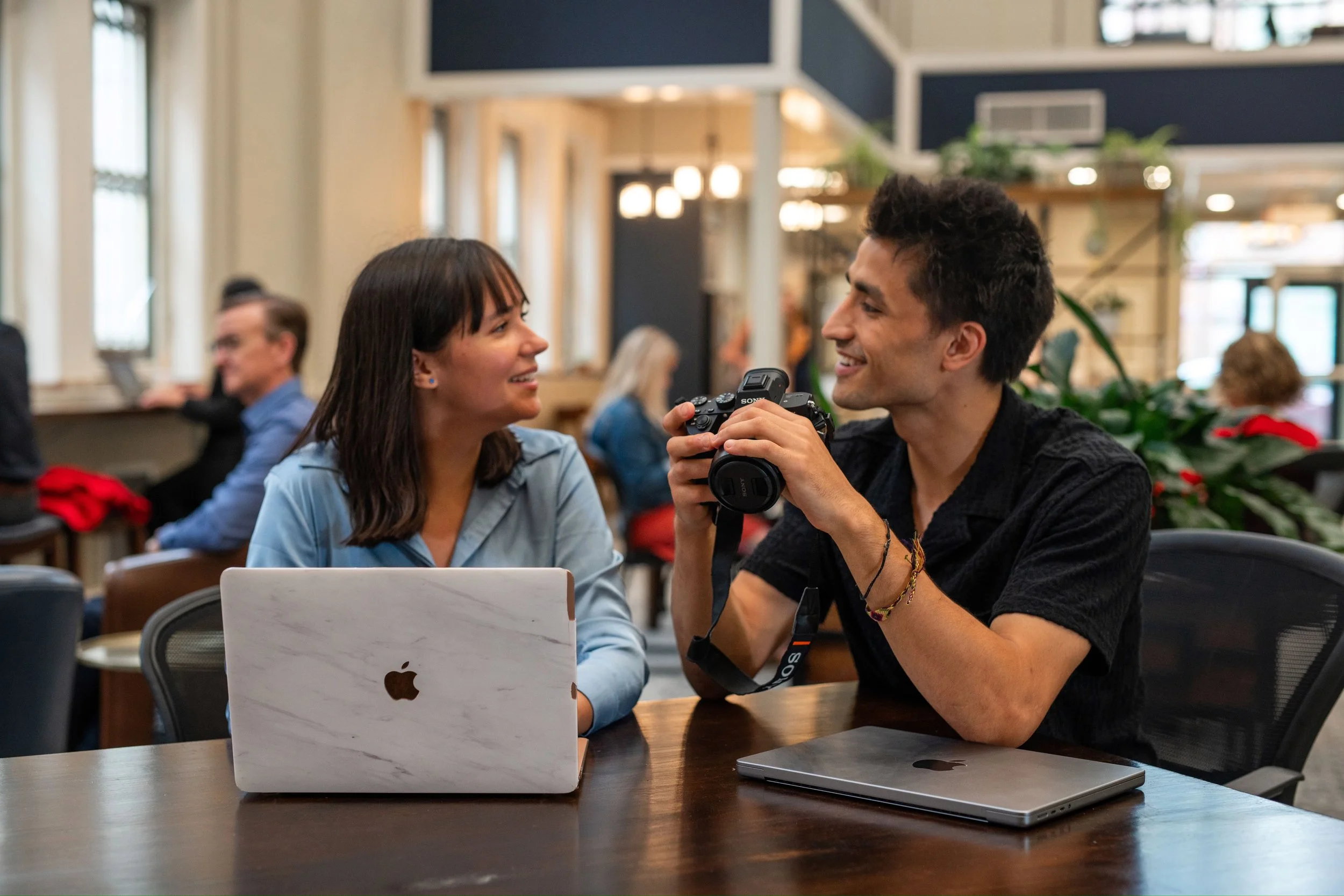 A coworking space where individuals are working with laptops and enjoying conversation.