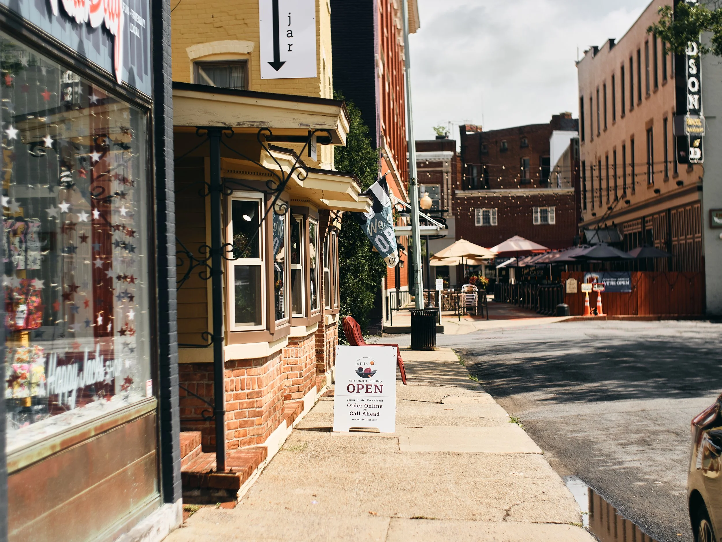 Downtown Glens Falls streetscape. buildings, business signs, tables and charis aling a sidewalk with lights strung above
