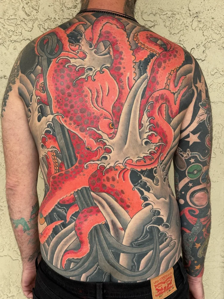 Japanese back piece tattoo of a red octopus in crashing waves