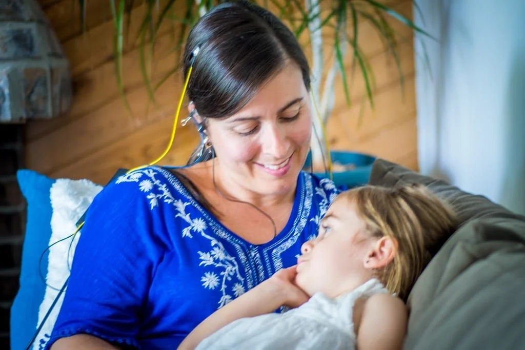 A woman receiving NeurOptimal® neurofeedback while looking lovingly at a young girl.