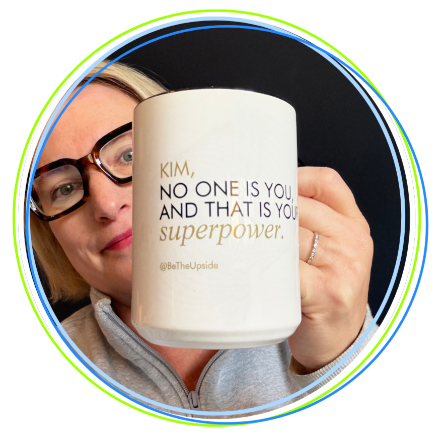 A woman with blonde hair and glasses holding a white mug with motivational writing, smiling. The background is black, and there is a colorful border around the image.