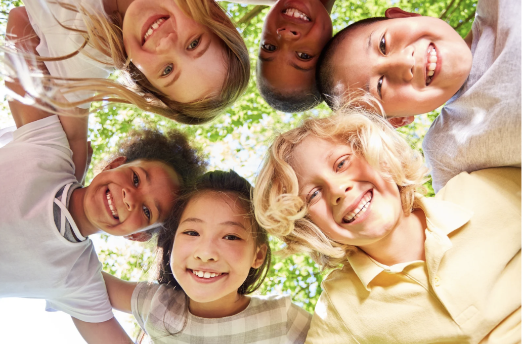 Children in a circle looking down at the camera