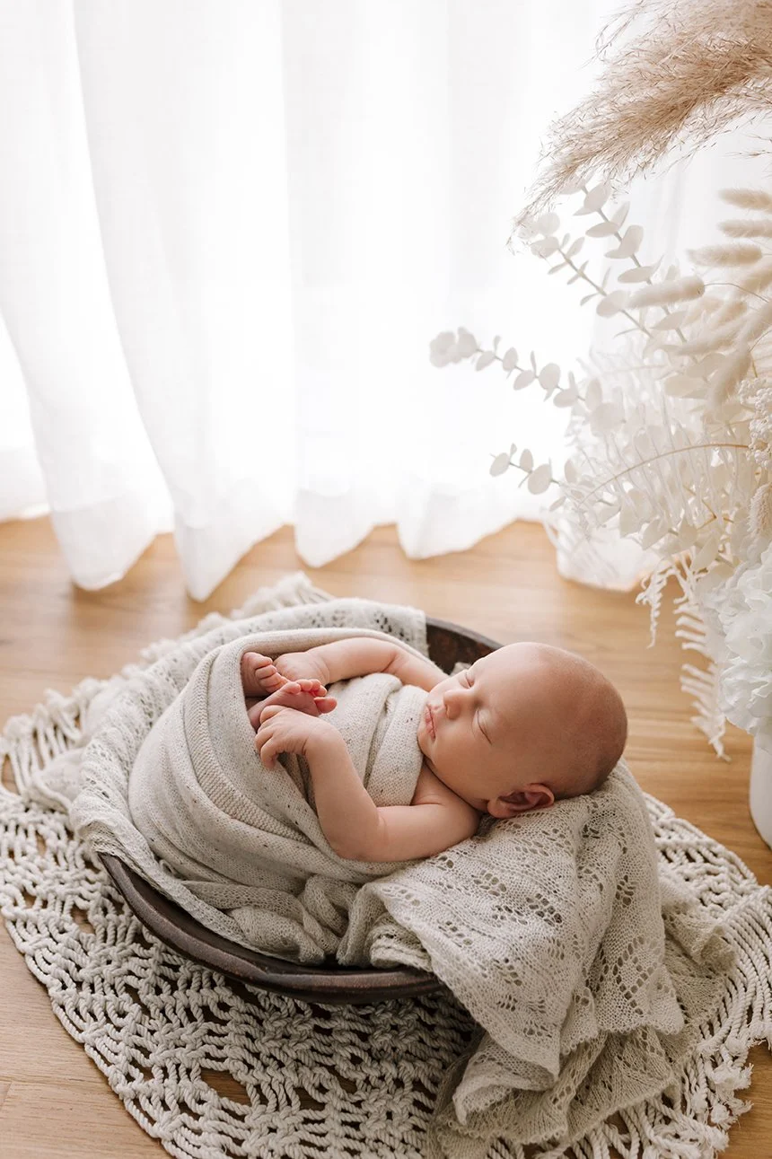 Newborn baby swaddled in soft blanket sleeping in a basket