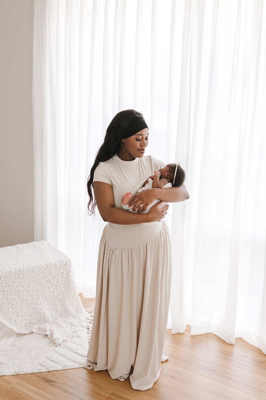 New mum gazing at her newborn baby in a natural studio portrait.