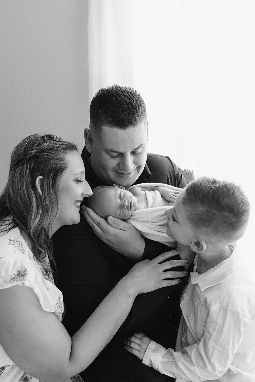 Family of four cuddling together during a newborn photography session.