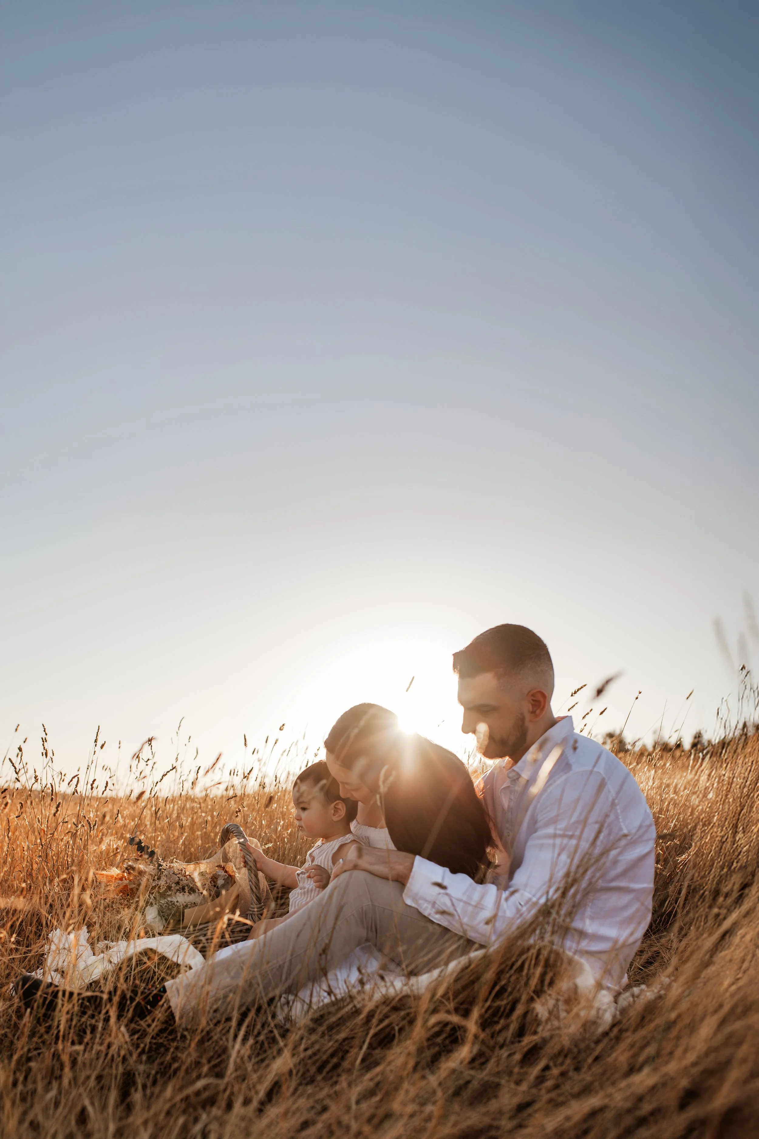 Parents cuddling their children at golden hour during an outdoor family session.