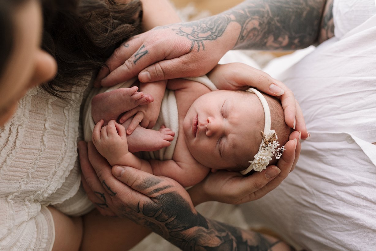 Close up image of parents hands holding their newborn baby