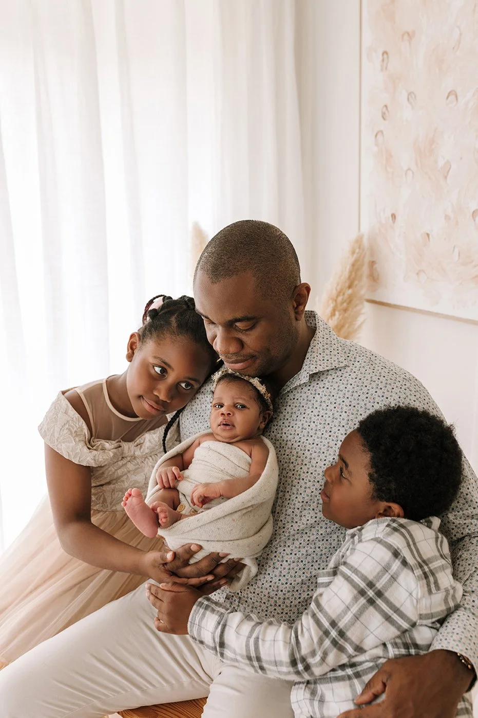 Father embracing his older children and newborn baby