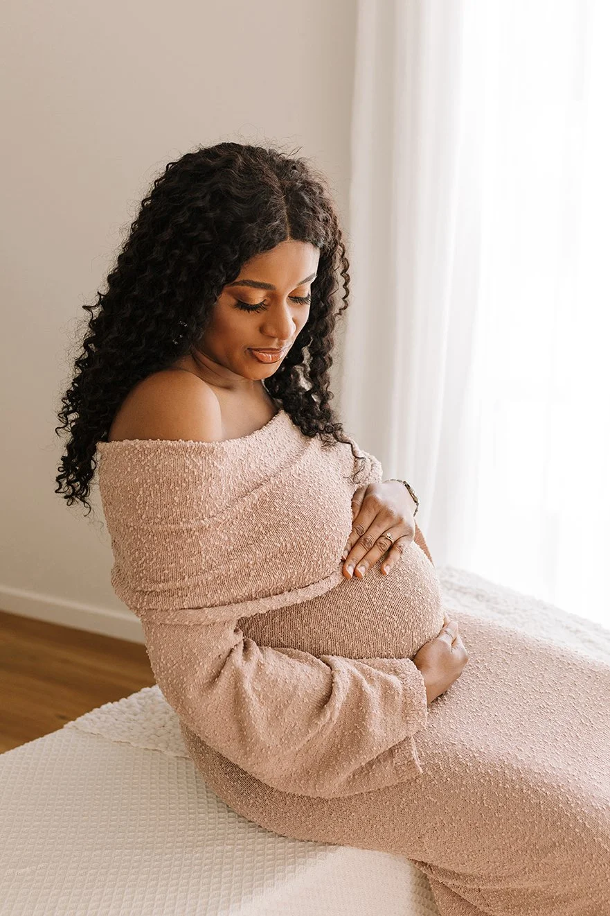 Pregnant woman holding her baby bump during a studio maternity session.