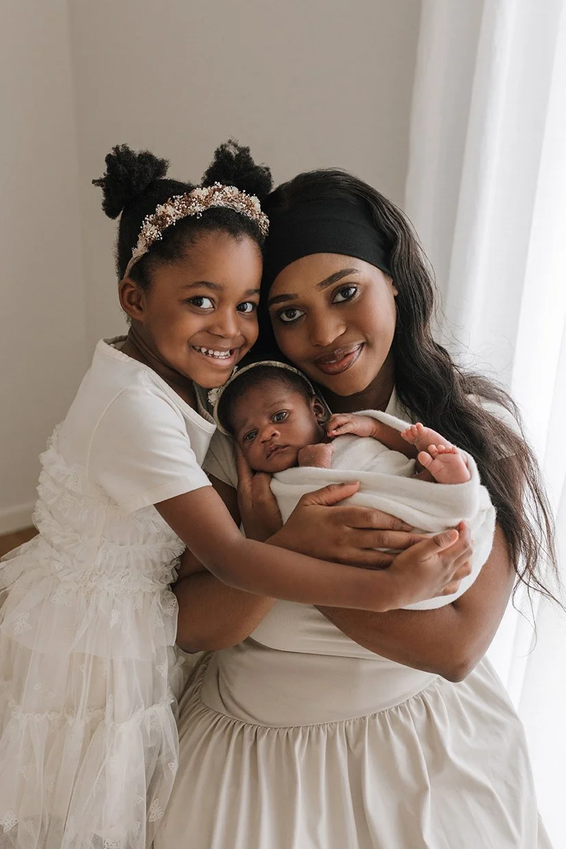 Mum and daughter cuddling newborn baby in family portrait