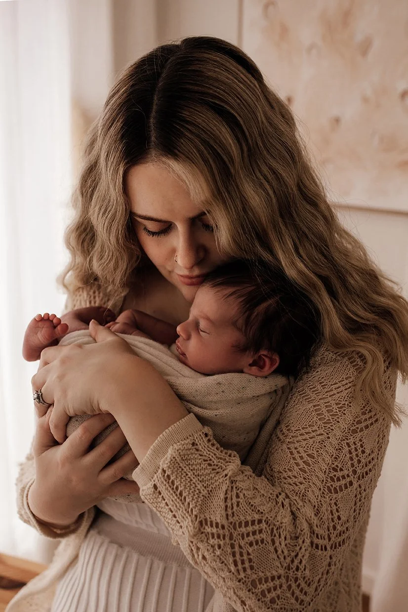 Mother embracing her newborn during a relaxed studio session.