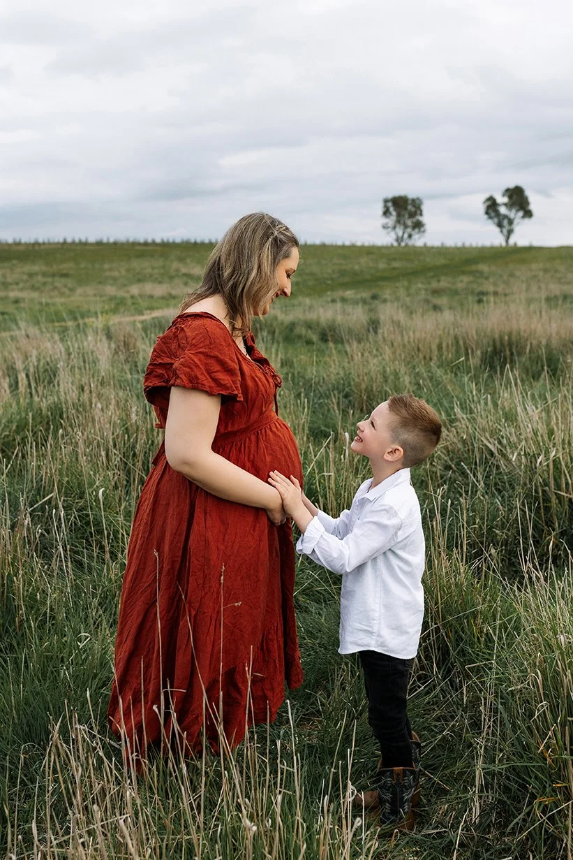 Pregnant mother and her son holding hands during outdoor maternity photoshoot