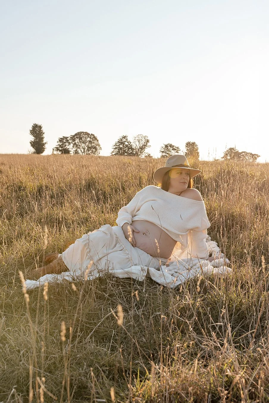 Mother-to-be holding her baby bump during a golden hour maternity session.