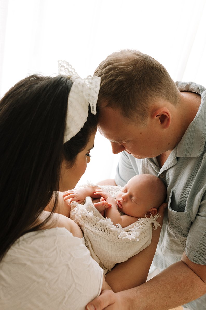 Newborn baby held lovingly between his parents