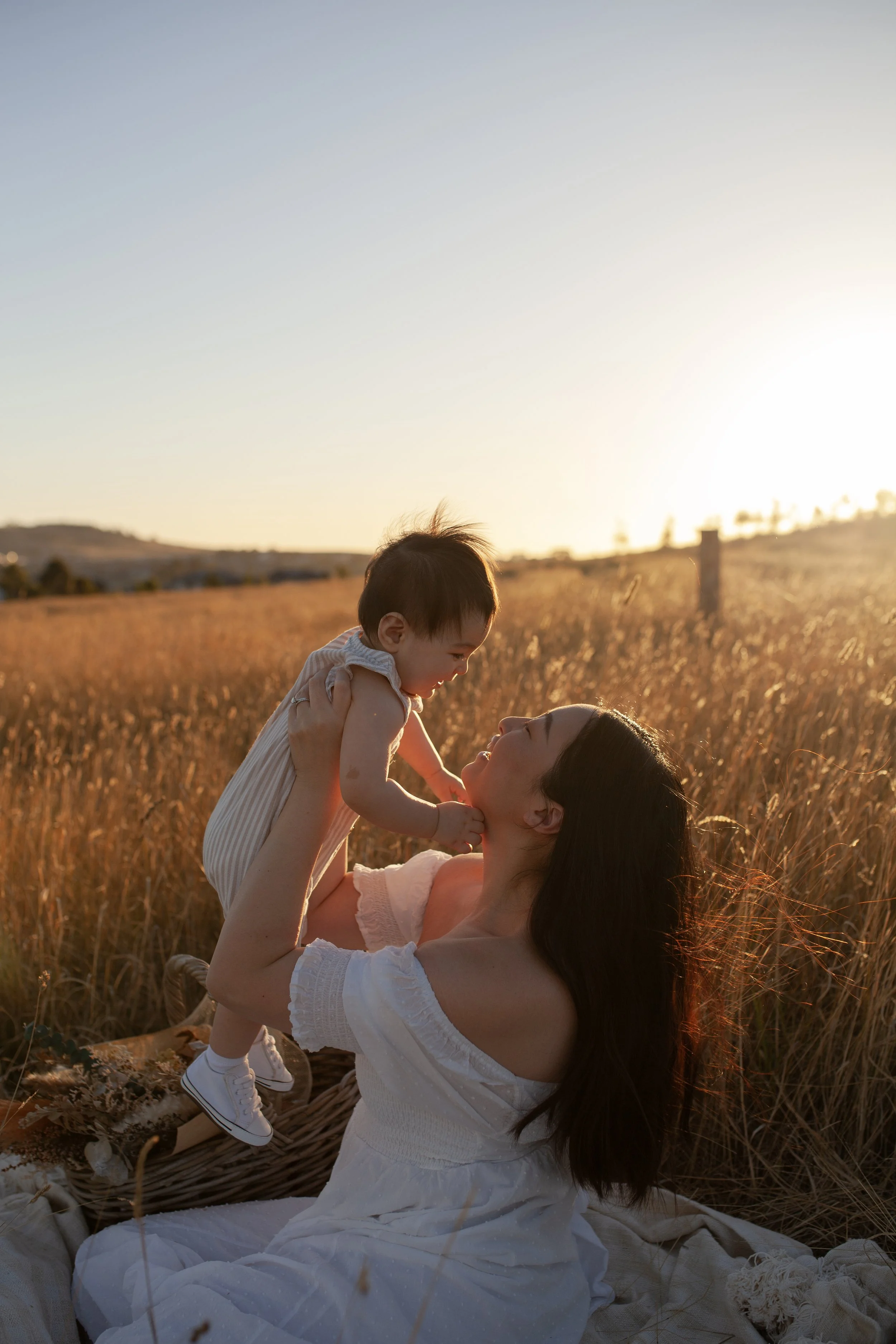 Mother holding her child in golden field at sunset
