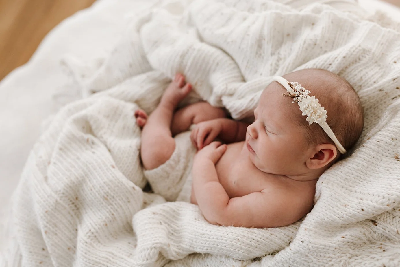 Newborn baby resting comfortably on a soft blanket.