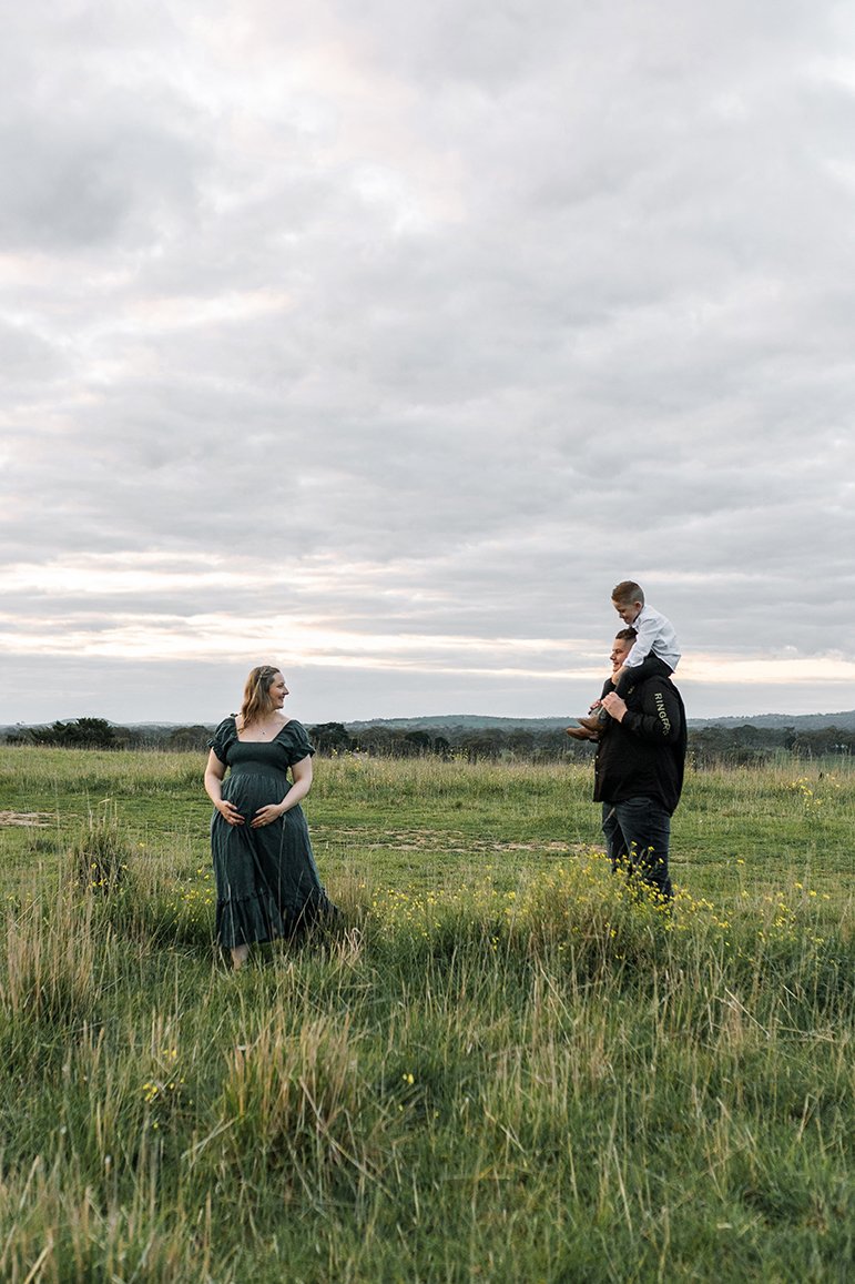 Family walking through field during a maternity photoshoot.
