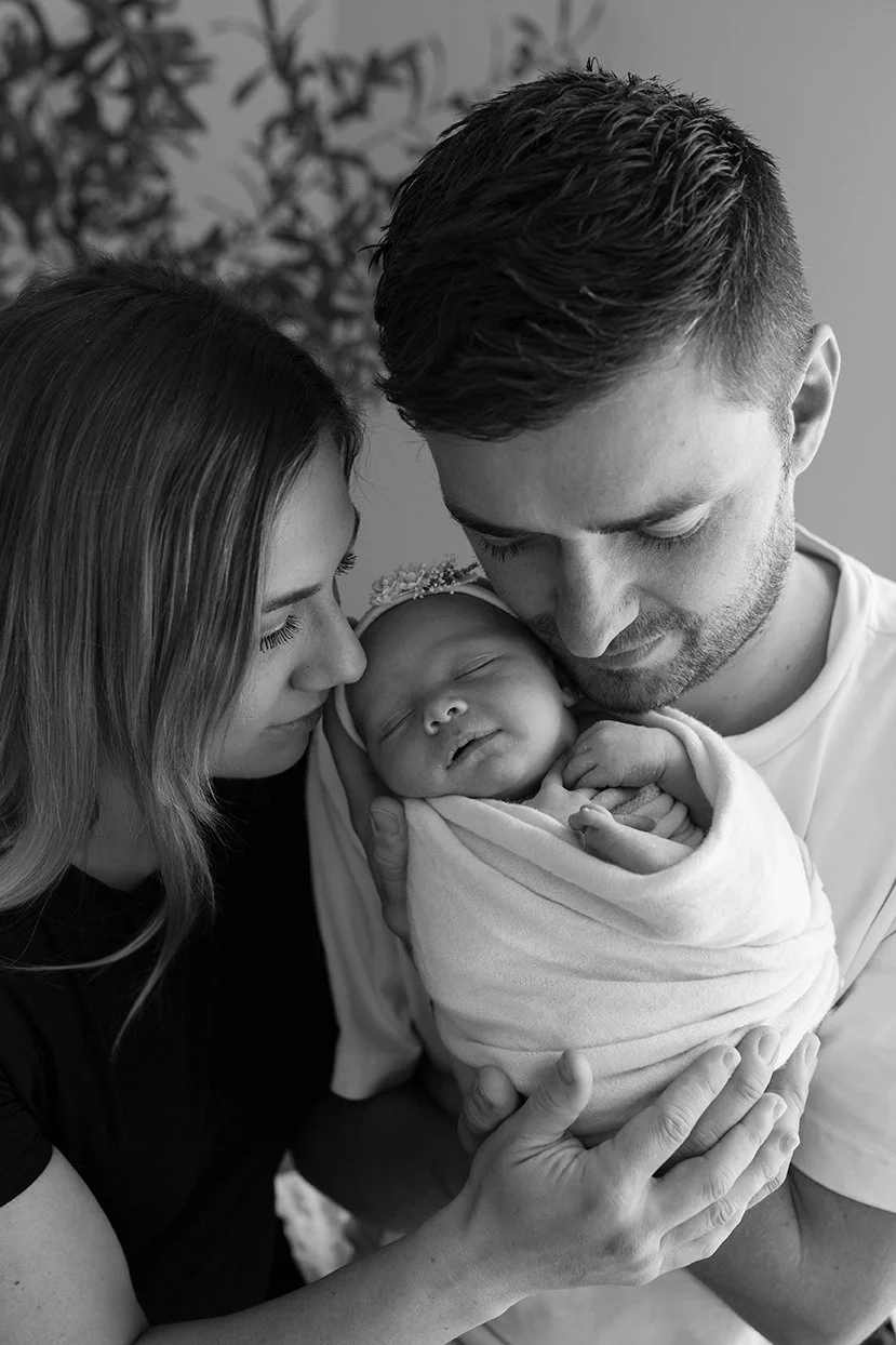 Newborn baby nestled safely in their parent's arms.