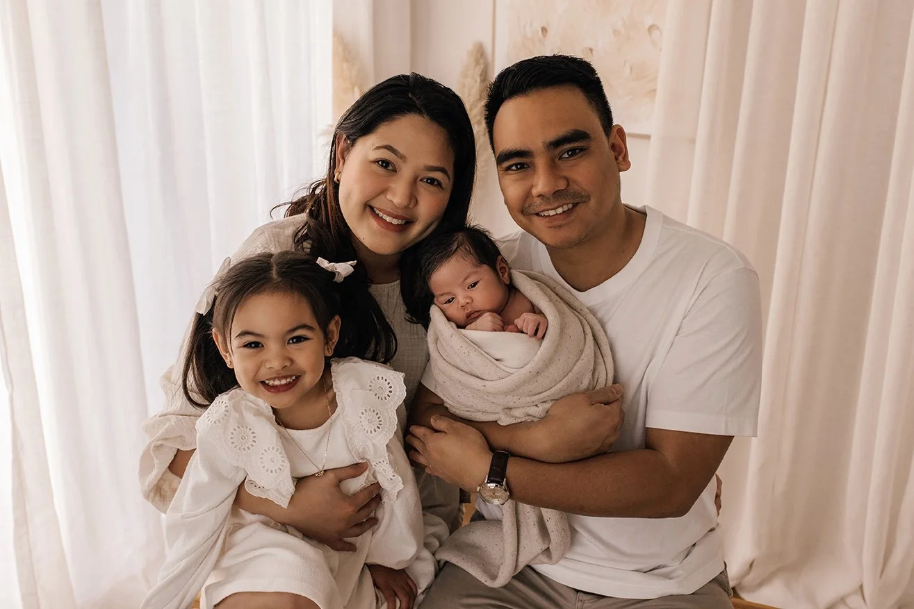 Family portrait captured in a warm and neutral studio setting.