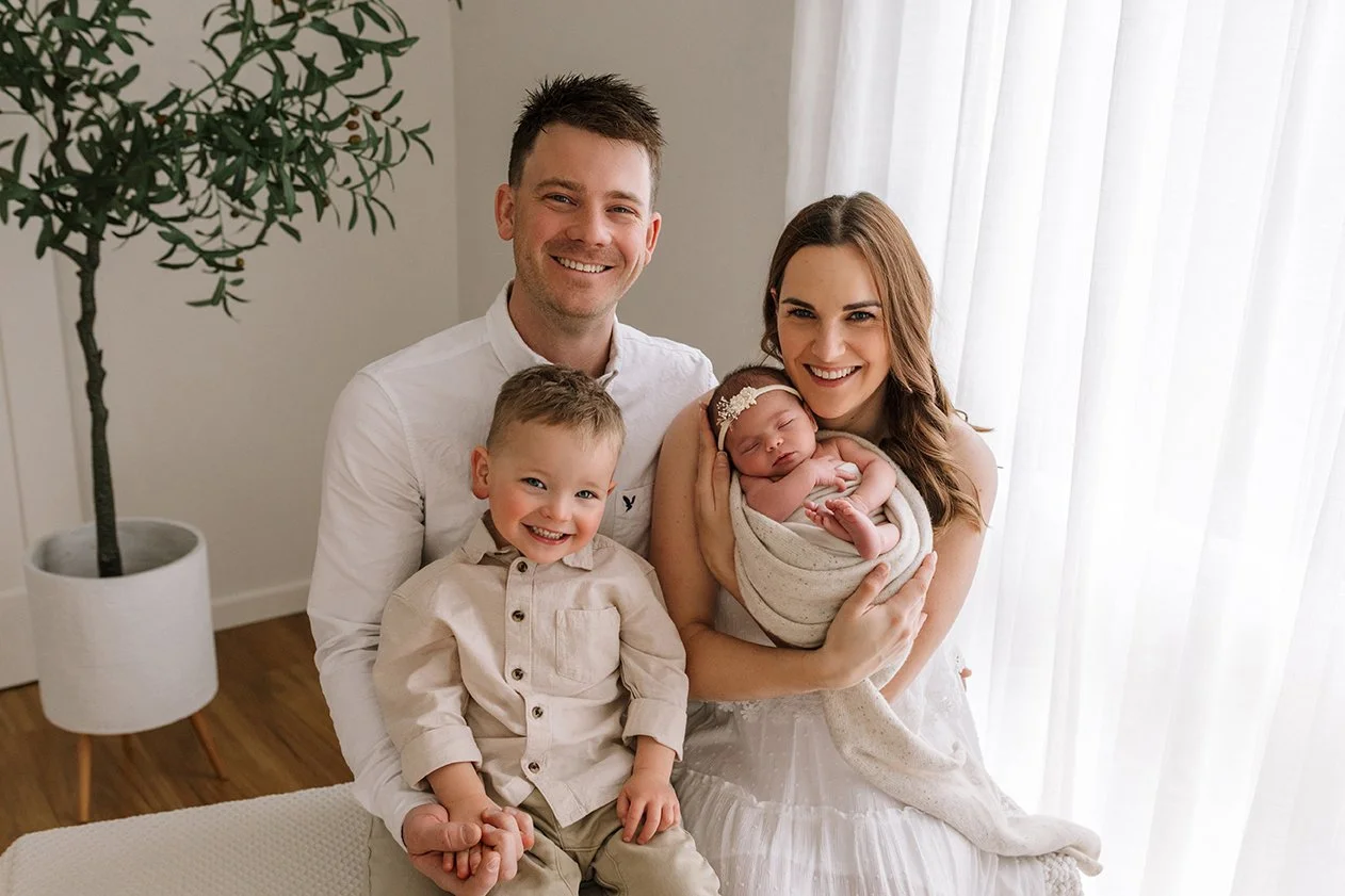 Family portrait captured in a warm and neutral studio setting.