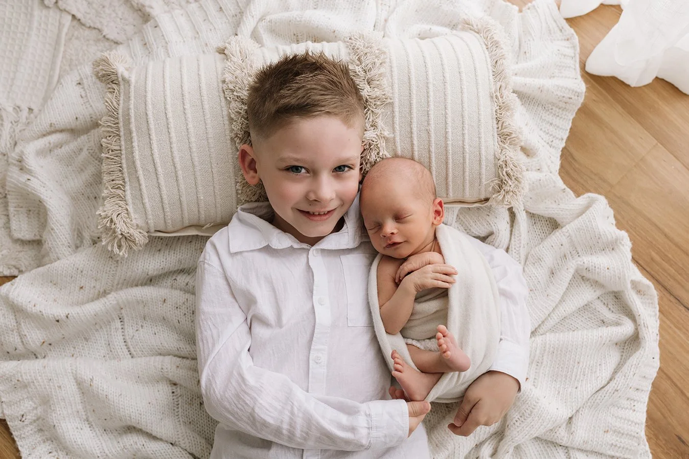 Older sibling cuddling their newborn baby brother.