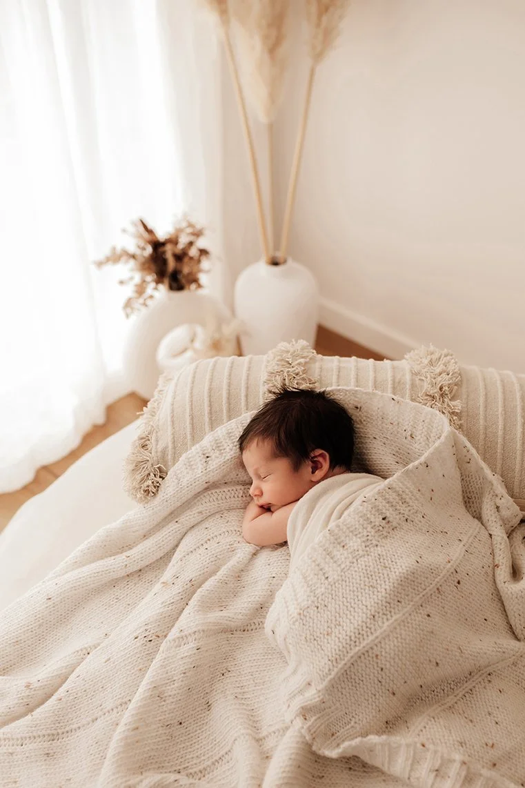 Newborn baby sleeping peacefully on soft blankets.