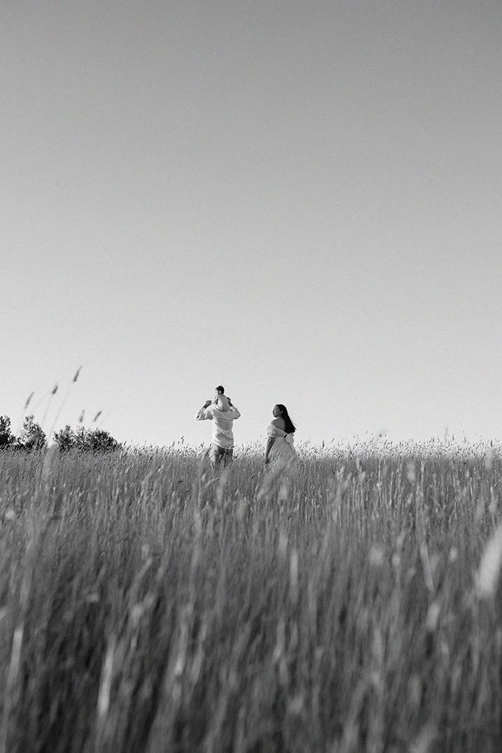 Family walking through open field at sunset
