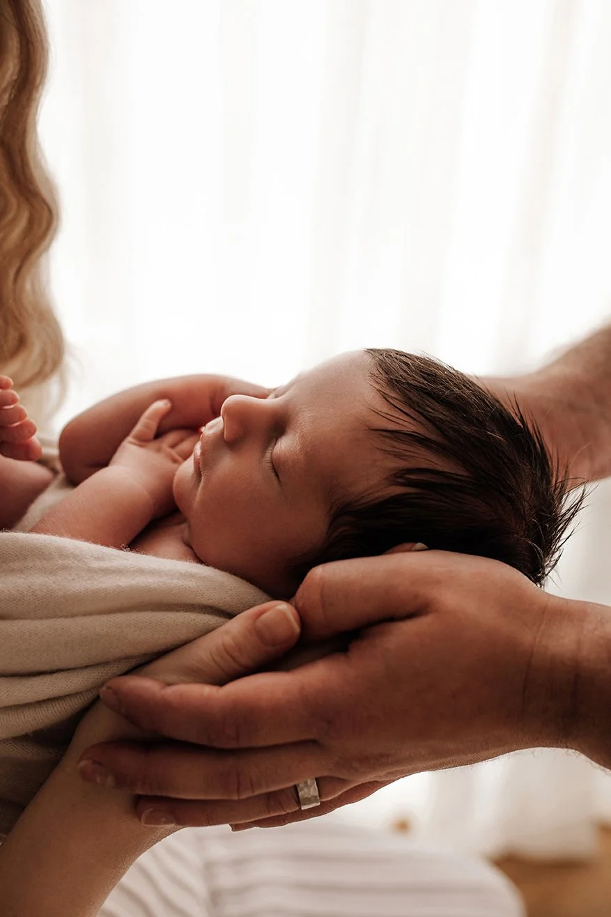 Parents hands cradling their newborn baby.