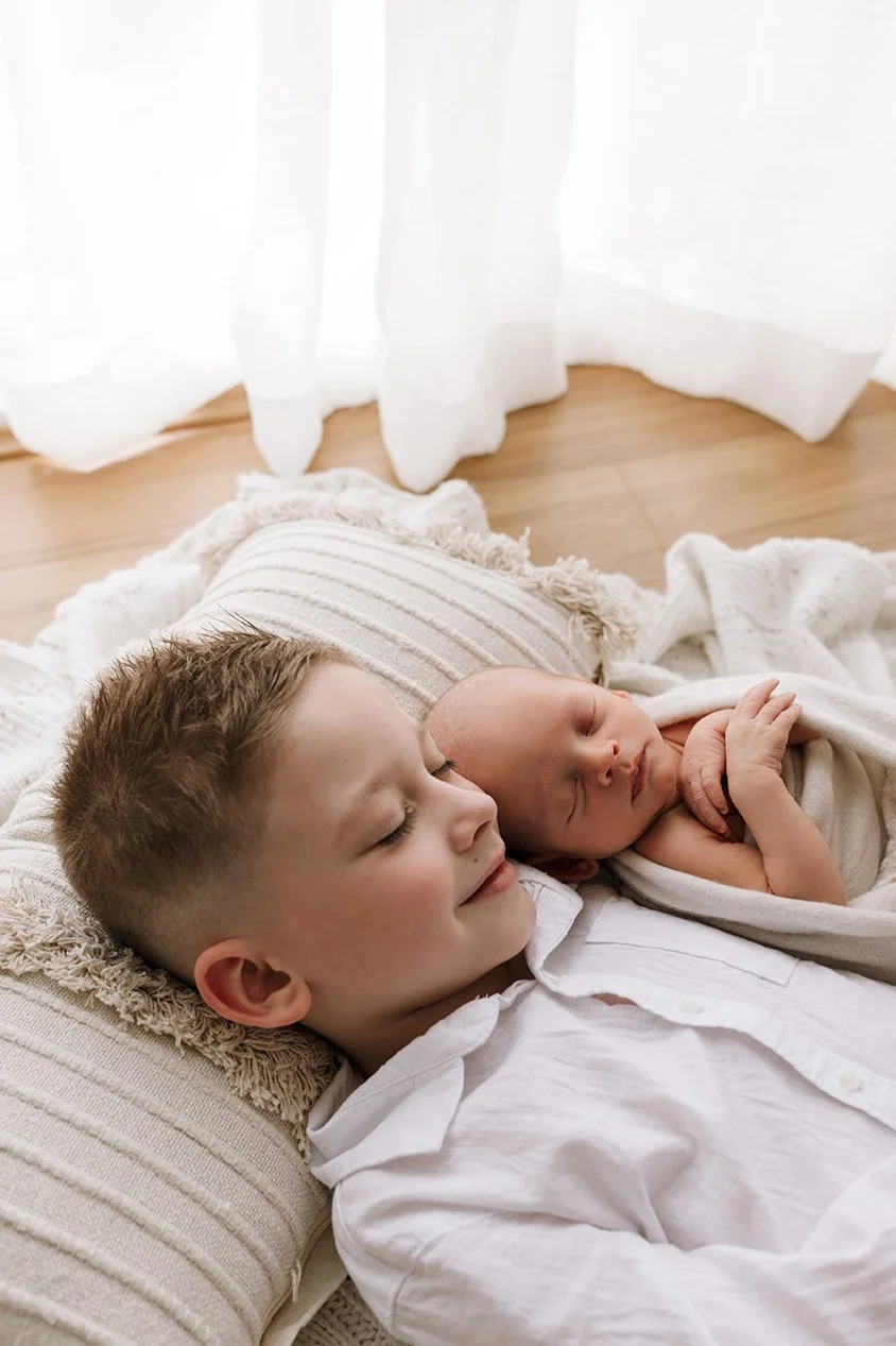 Siblings cuddling in natural light newborn session