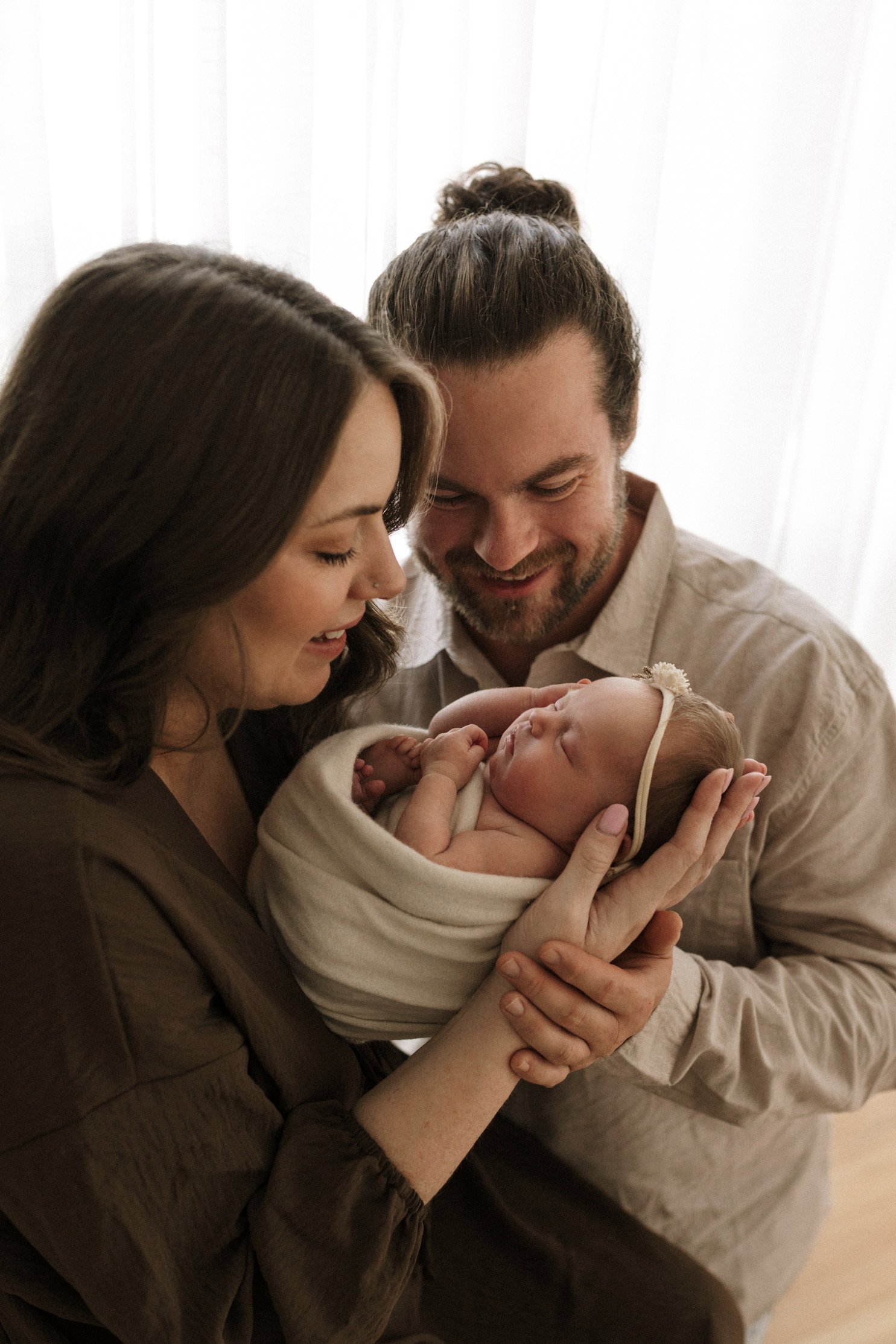 New parents looking lovingly a newborn baby
