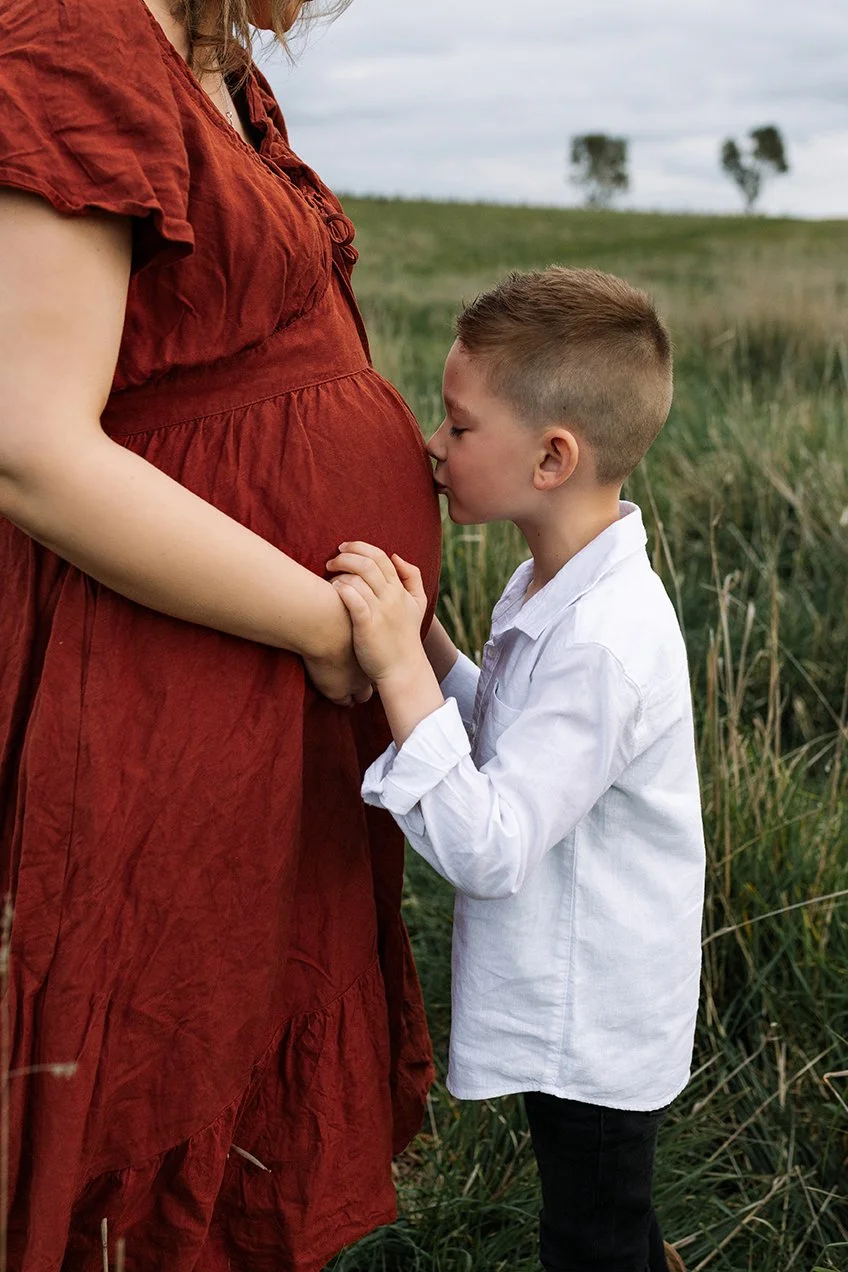 Child kissing his pregnant mother's stomach 