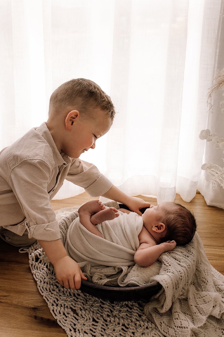 Older brother looking lovingly at his newborn sibling
