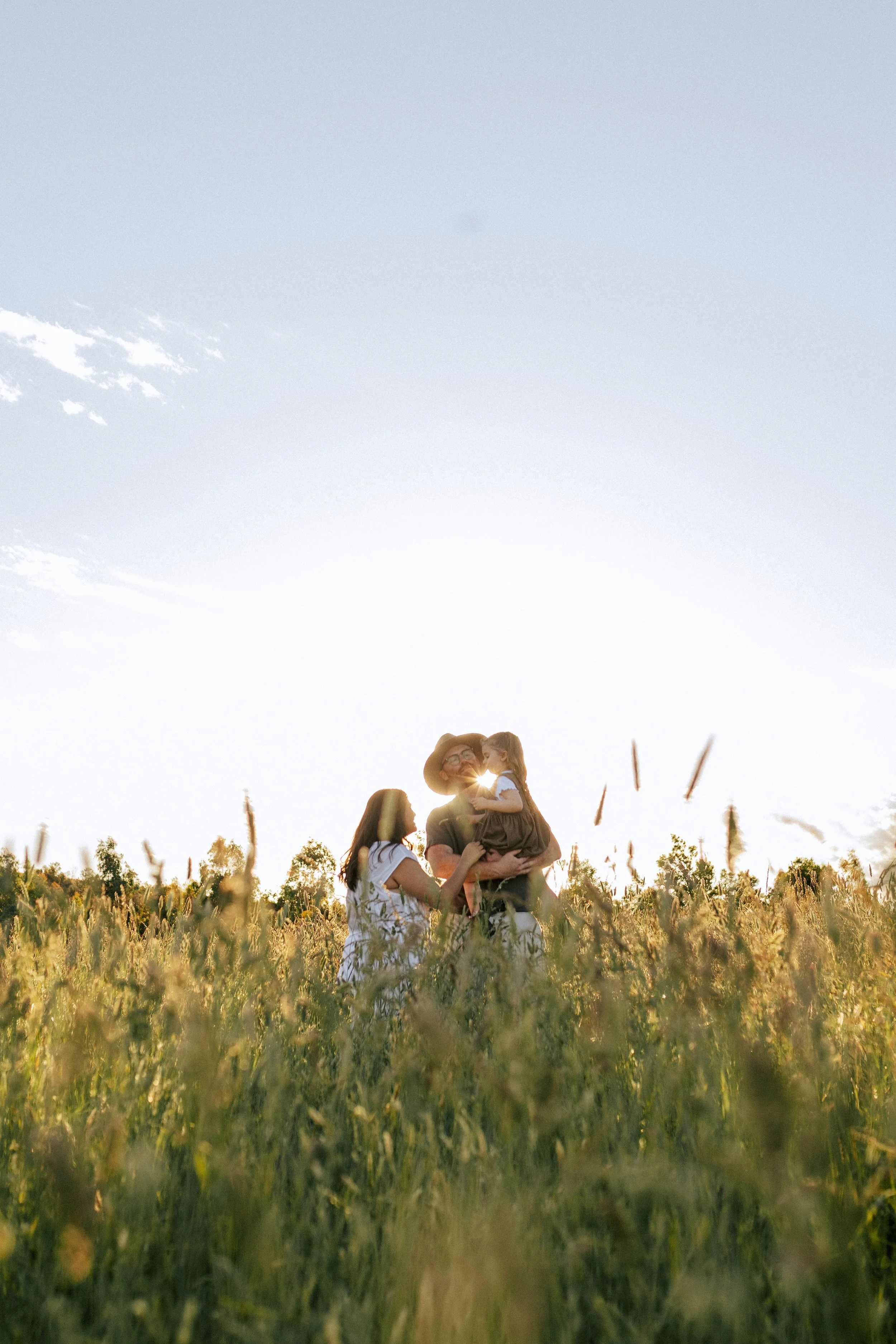 Family standing together in long grass at golden hour