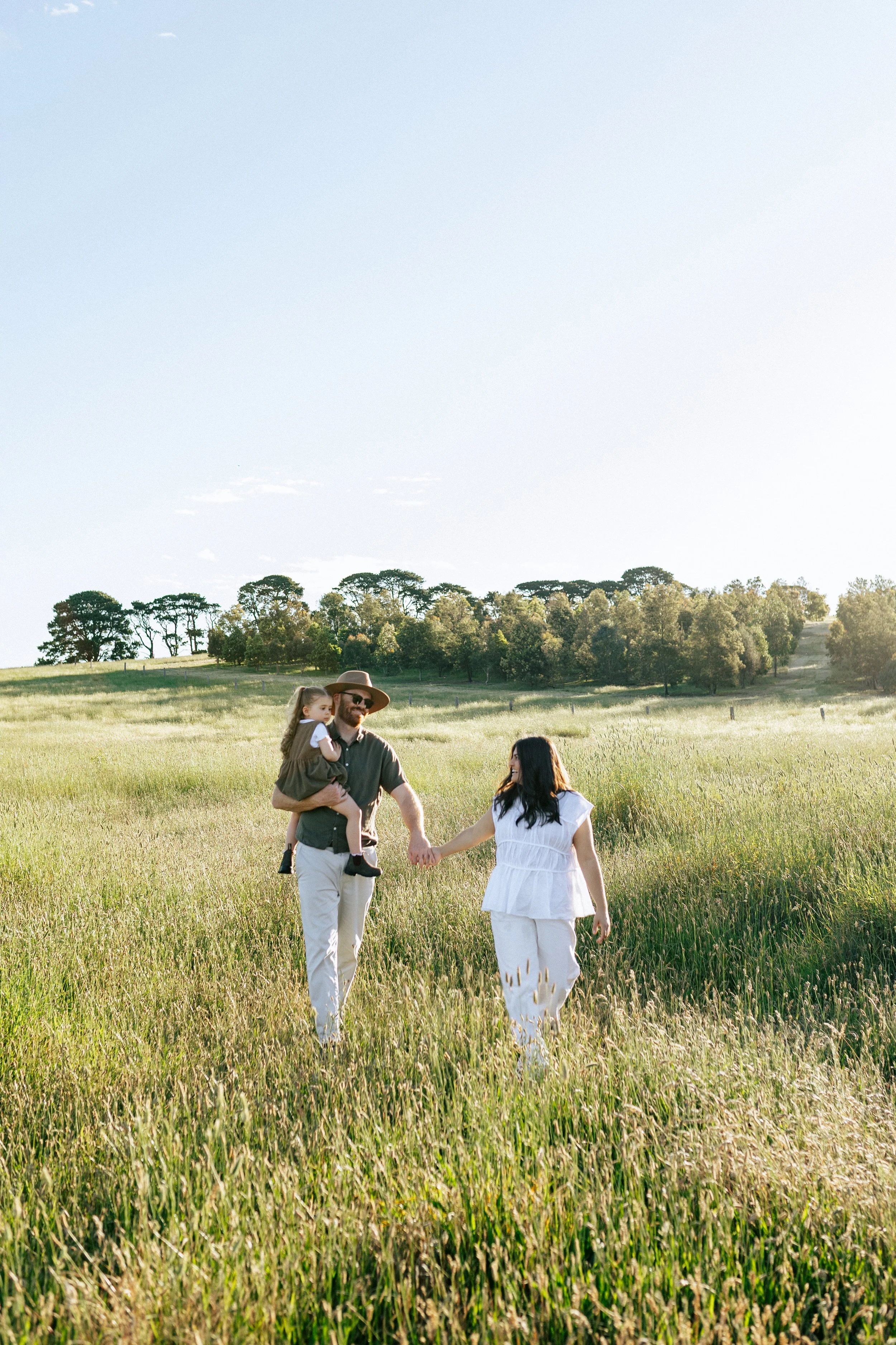 Family walking through field at sunset
