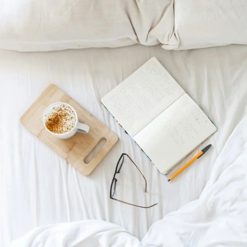 Open notebook, pen, and coffee on a white bed, creating a calm space for brand reflection and goal setting in 2026.