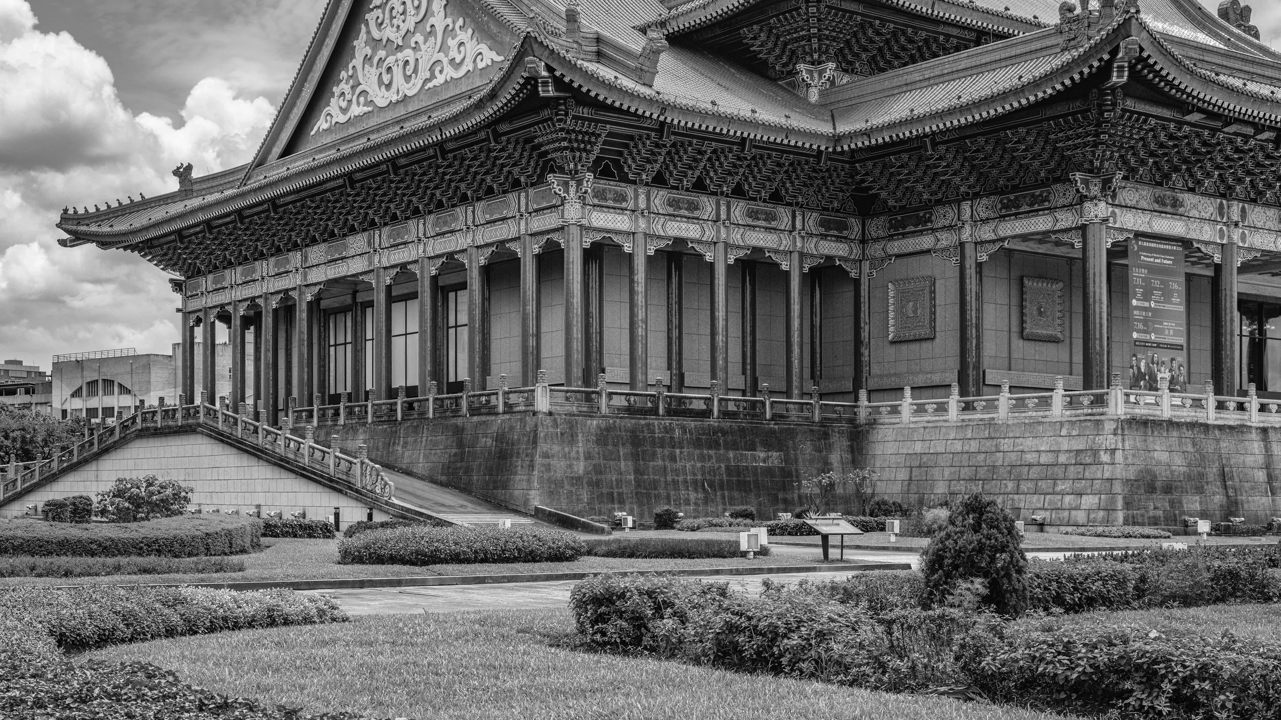 Black and white photo of a traditional Asian temple with ornate roof details, surrounded by a landscaped garden.