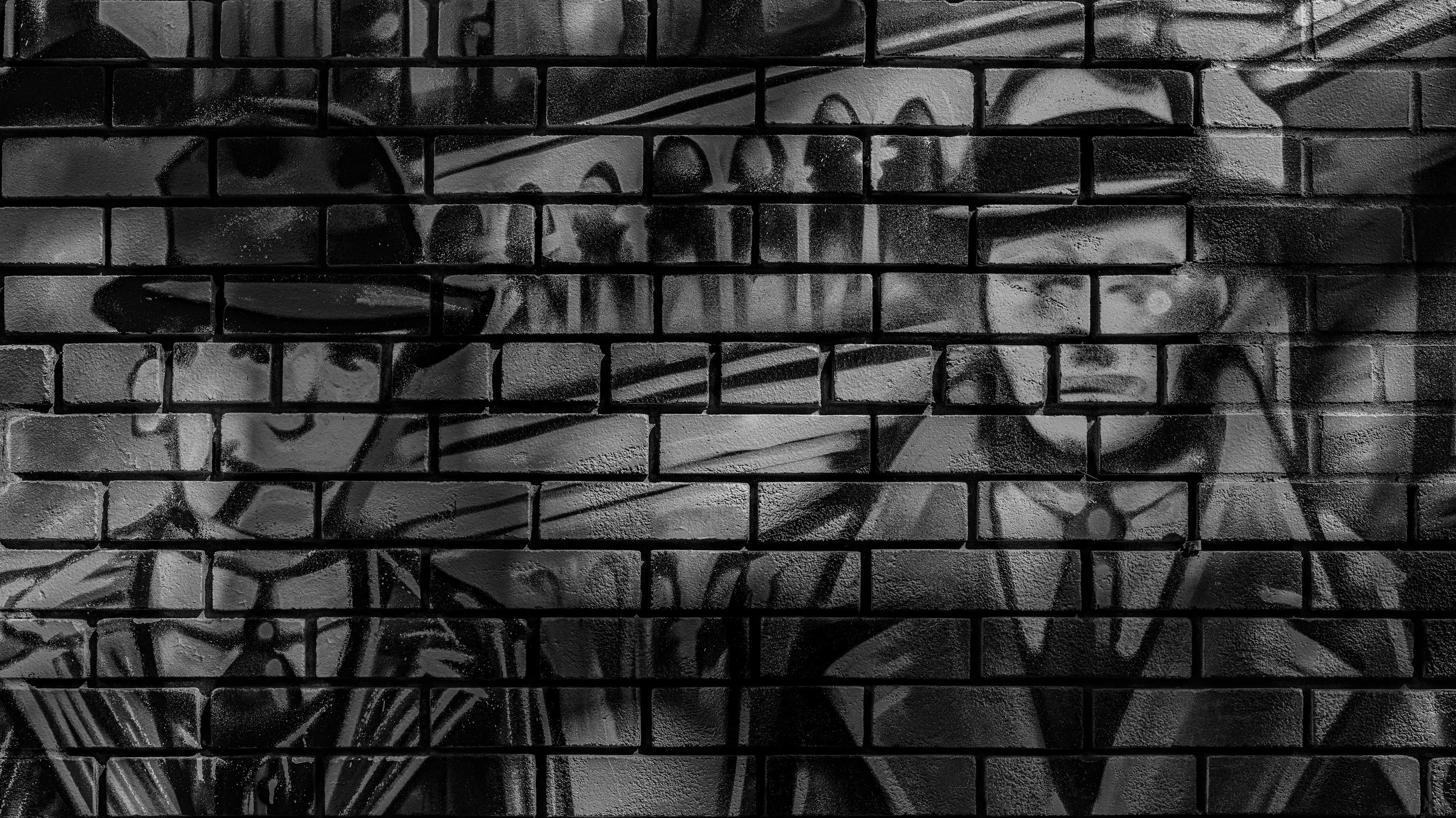 Black and white graffiti art on a brick wall featuring abstract shapes and lines.