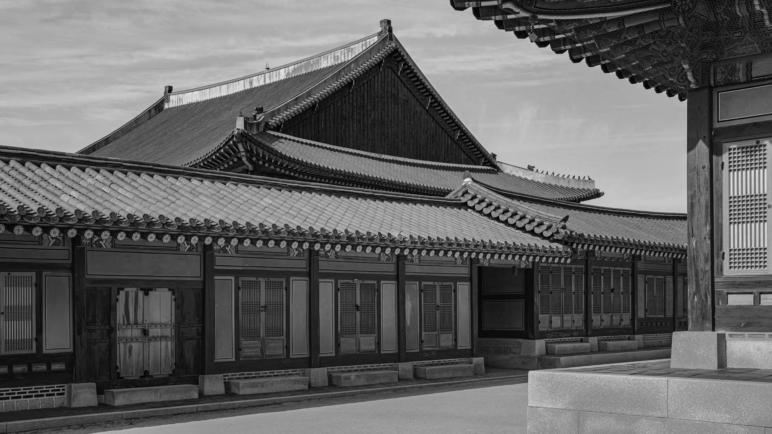 Black and white photo of traditional wooden Japanese temple buildings with tiled roofs and decorative carvings.