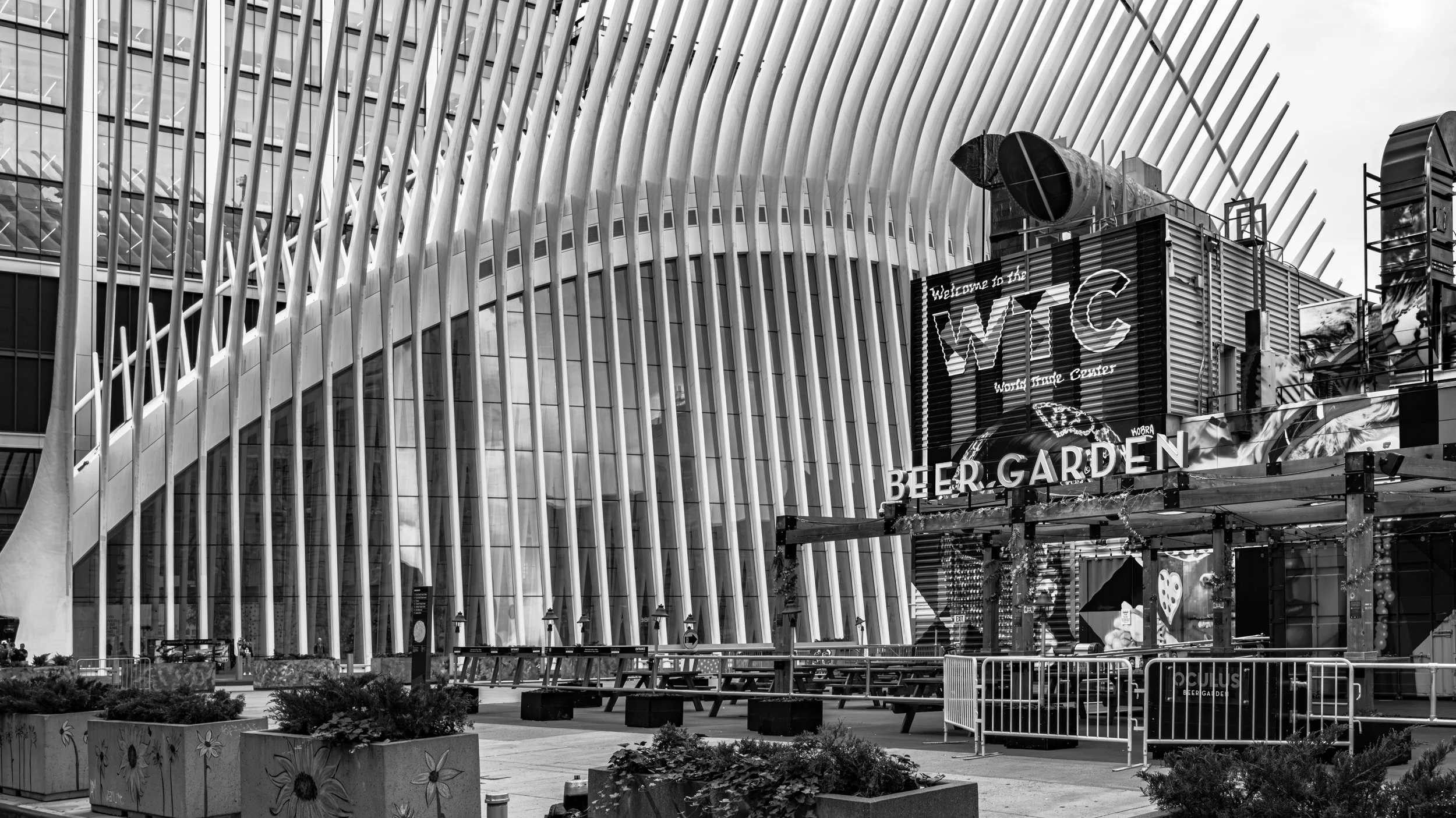 Black and white photo of Times Square in New York City, featuring modern buildings with architectural details, digital signs, and a visible sign that reads 'BEER GARDEN'. Manhattan, New York, USA.