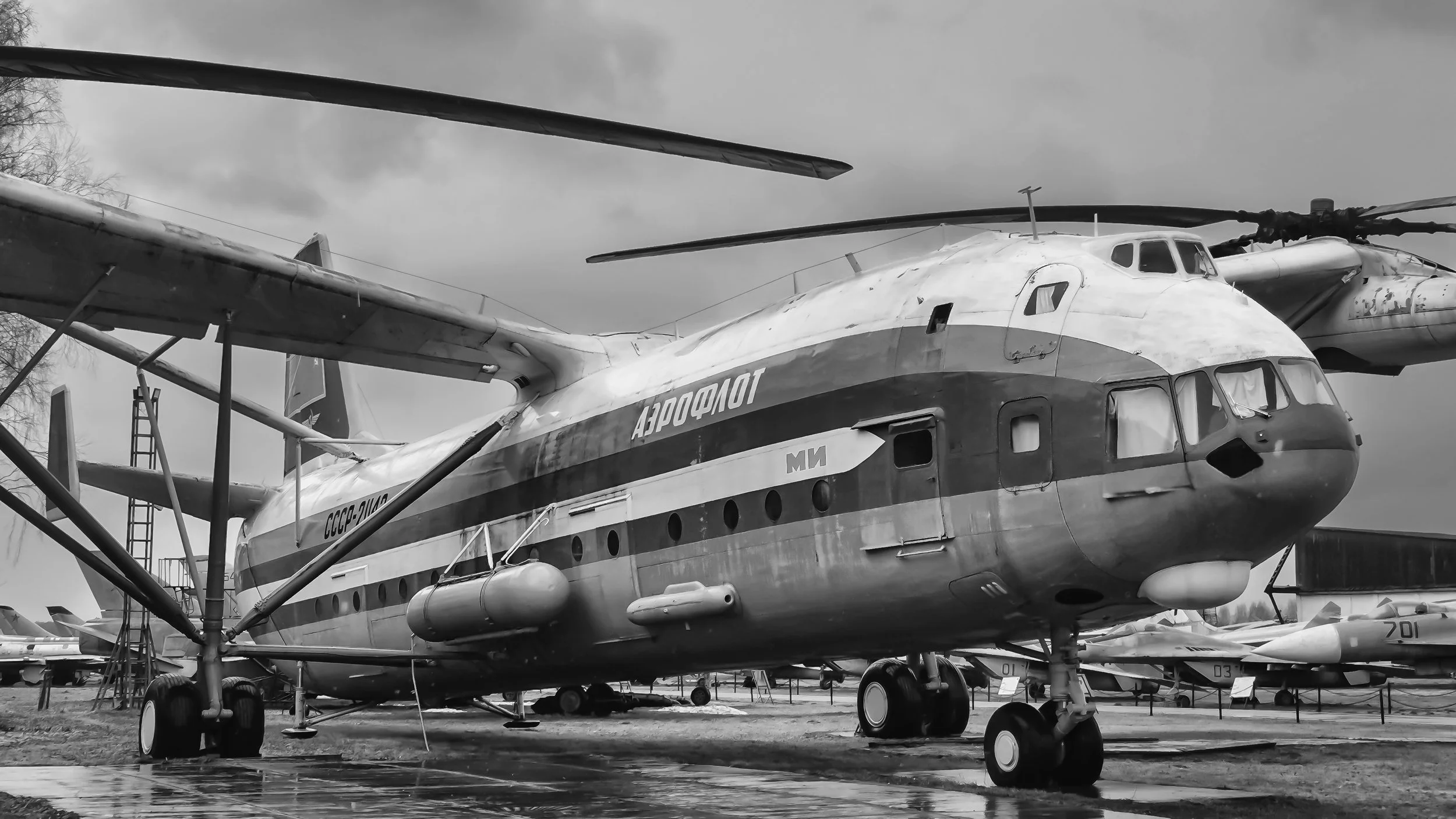 Black and white photograph of a military helicopter parked outdoors, with the word 'Аэрофлот' written on its side in Cyrillic script. Moscow, Russia.