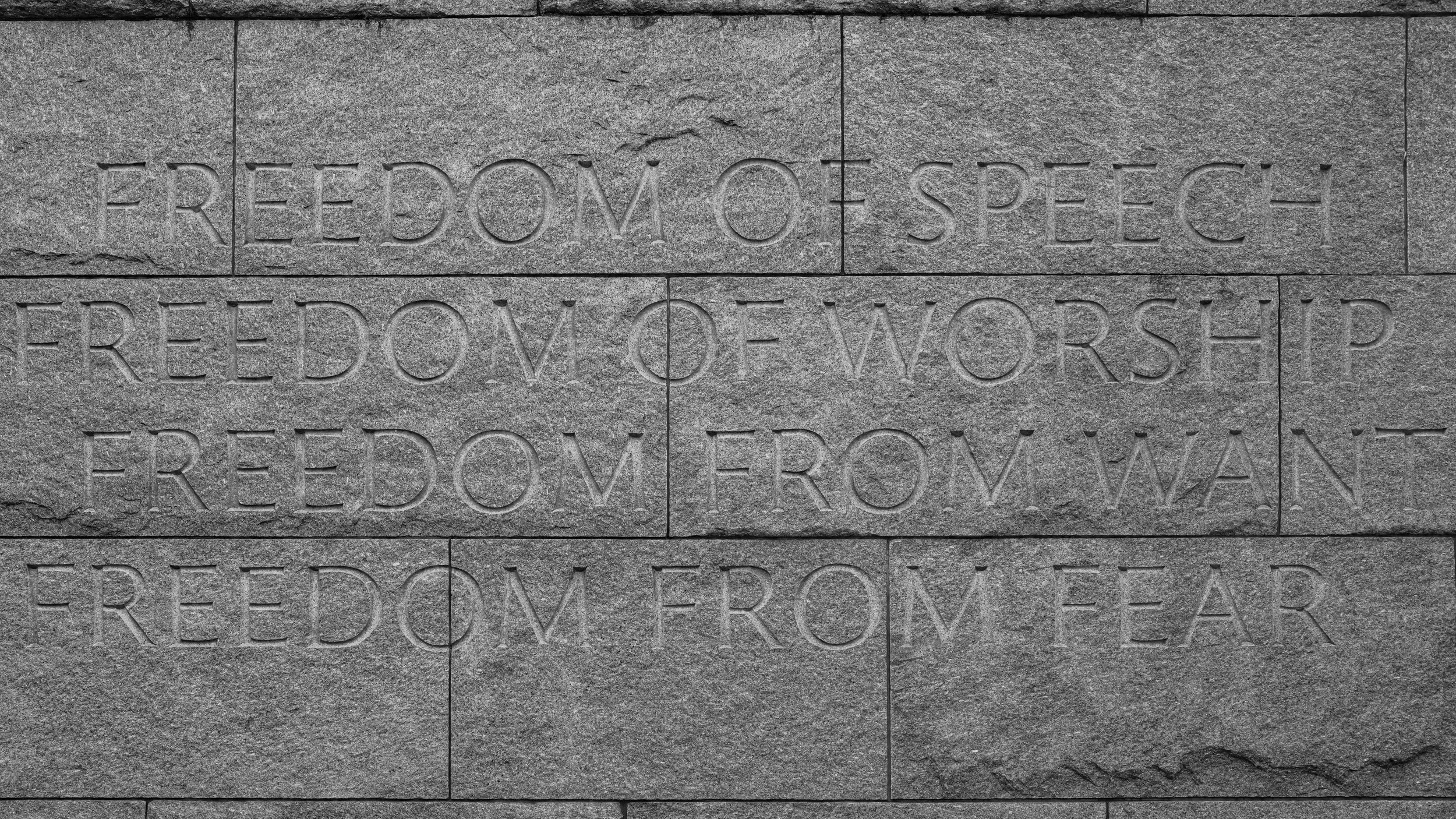 Stone wall with engraved words 'FREEDOM OF SPEECH' and 'FREEDOM OF WORSHIP'