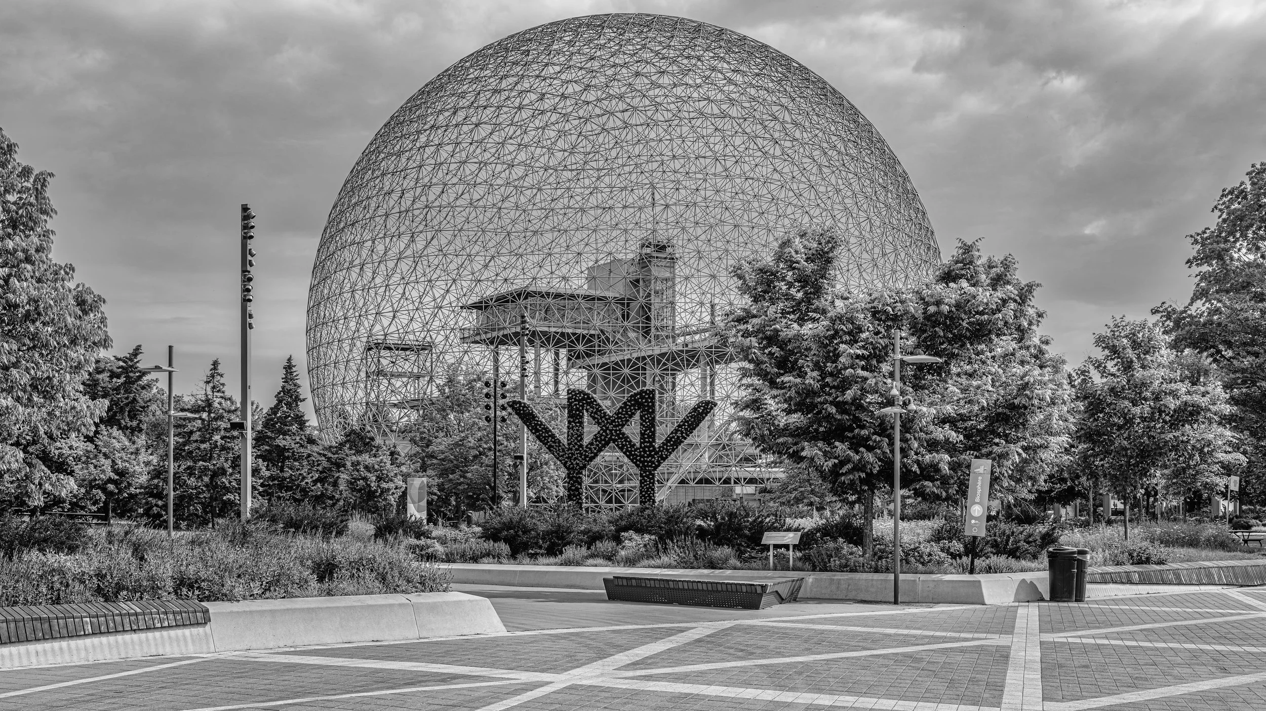 Black and white photo of the Montreal Biosphere surrounded by trees and a walkway.