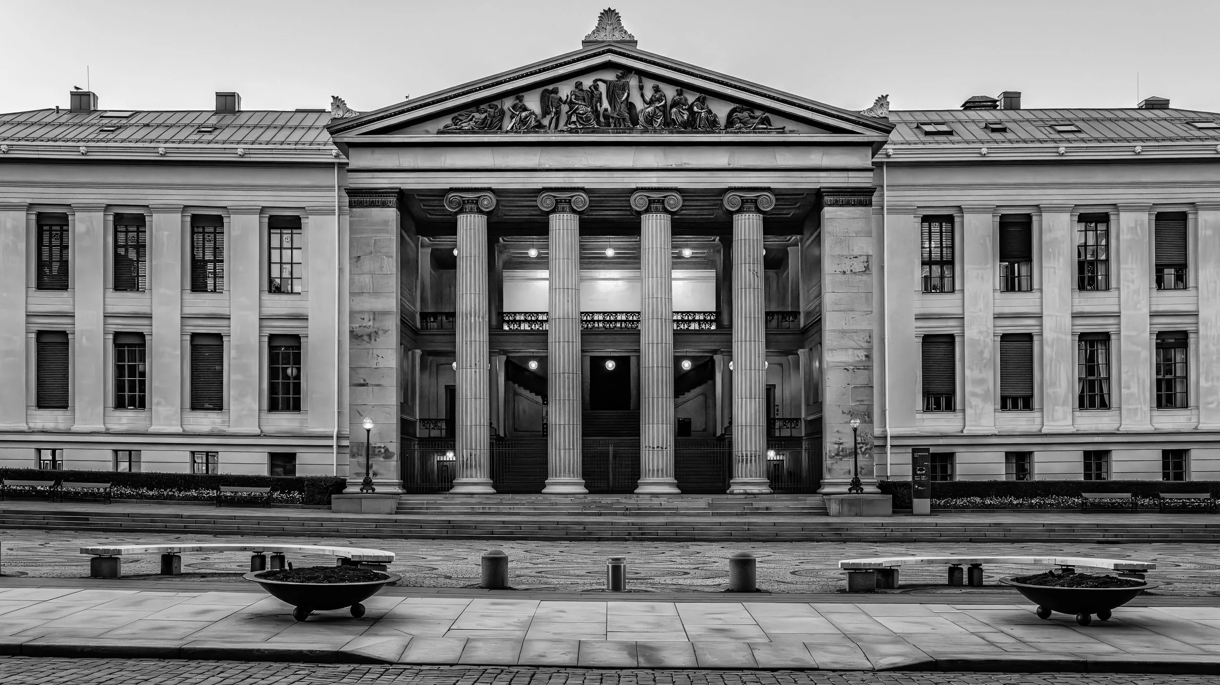 Front view of a classical-style building with four large columns supporting a triangular pediment featuring sculpted figures.