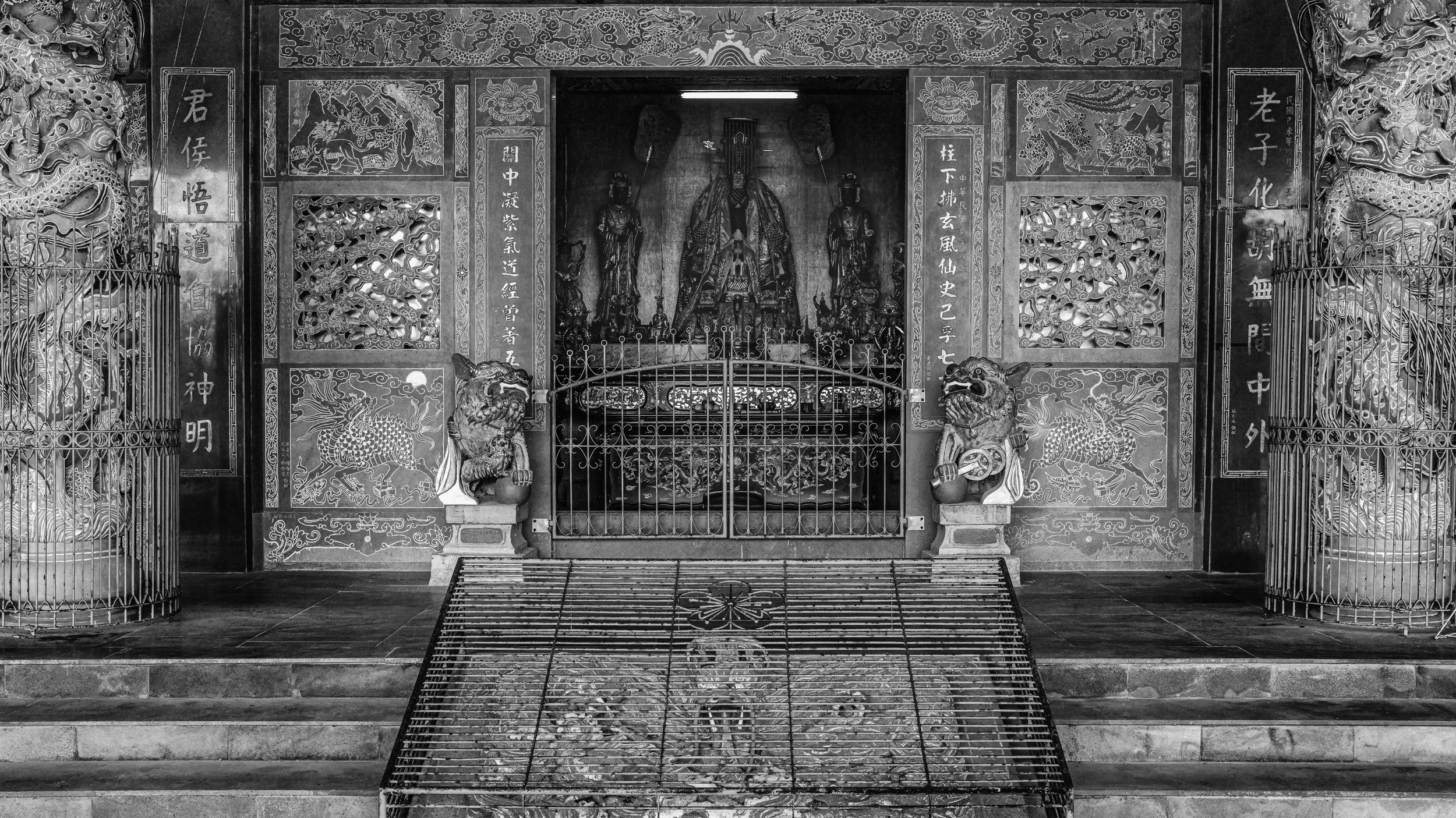 Black and white photo of an ornate Chinese altar with dragons and qilin statues, intricate wood carvings, and Chinese characters.