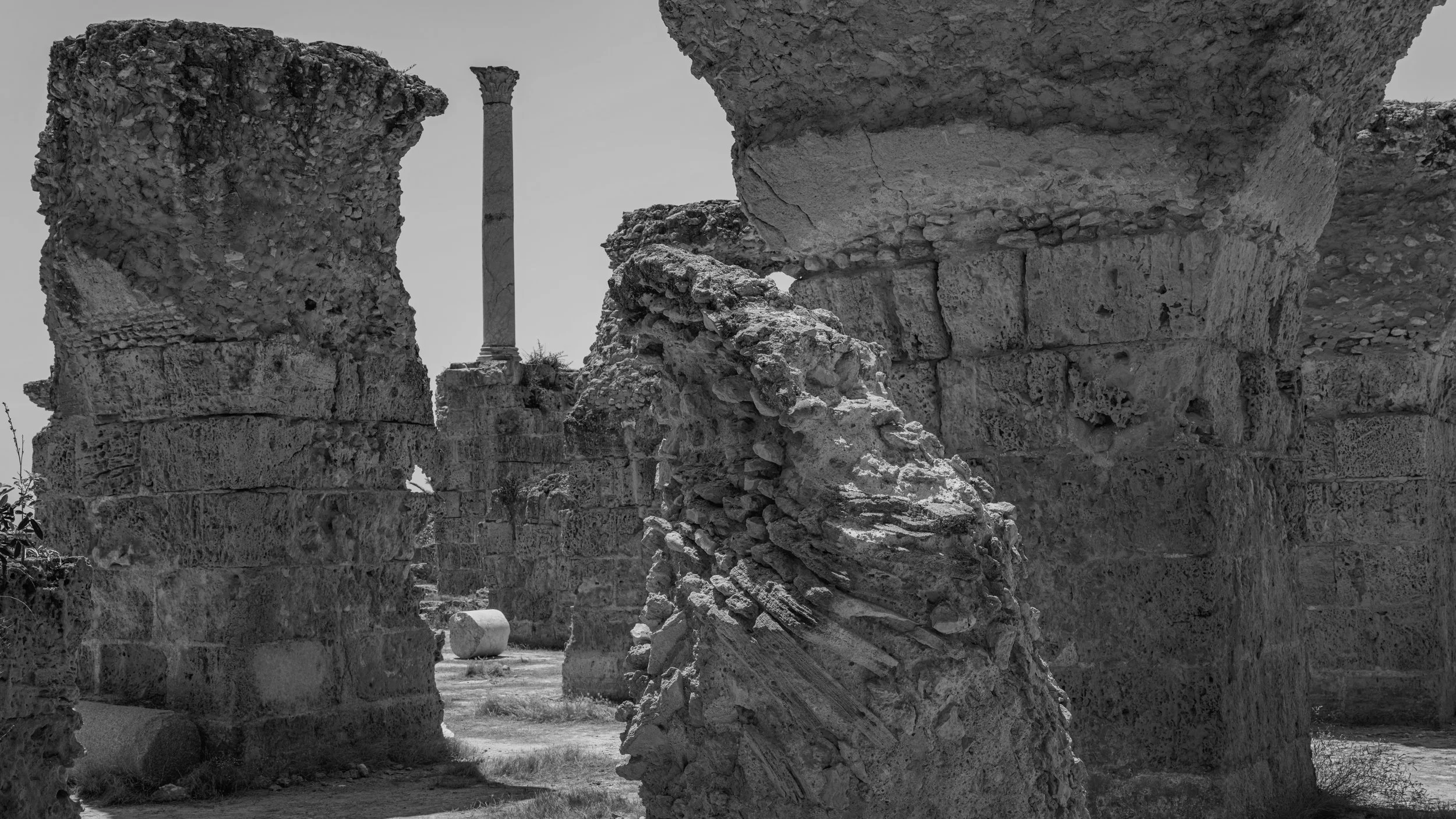 Ancient stone ruins with broken columns and scattered stones in a historical archaeological site.