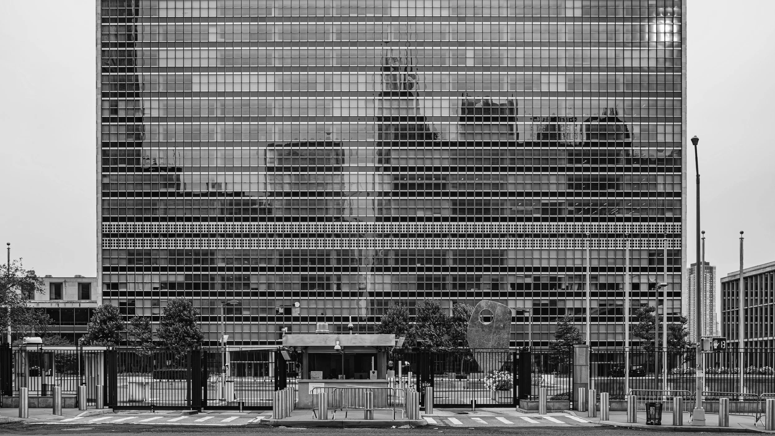 Reflected city skyline with tall buildings seen through the glass facade of a modern office building in black and white. Manhattan, New York, USA.
