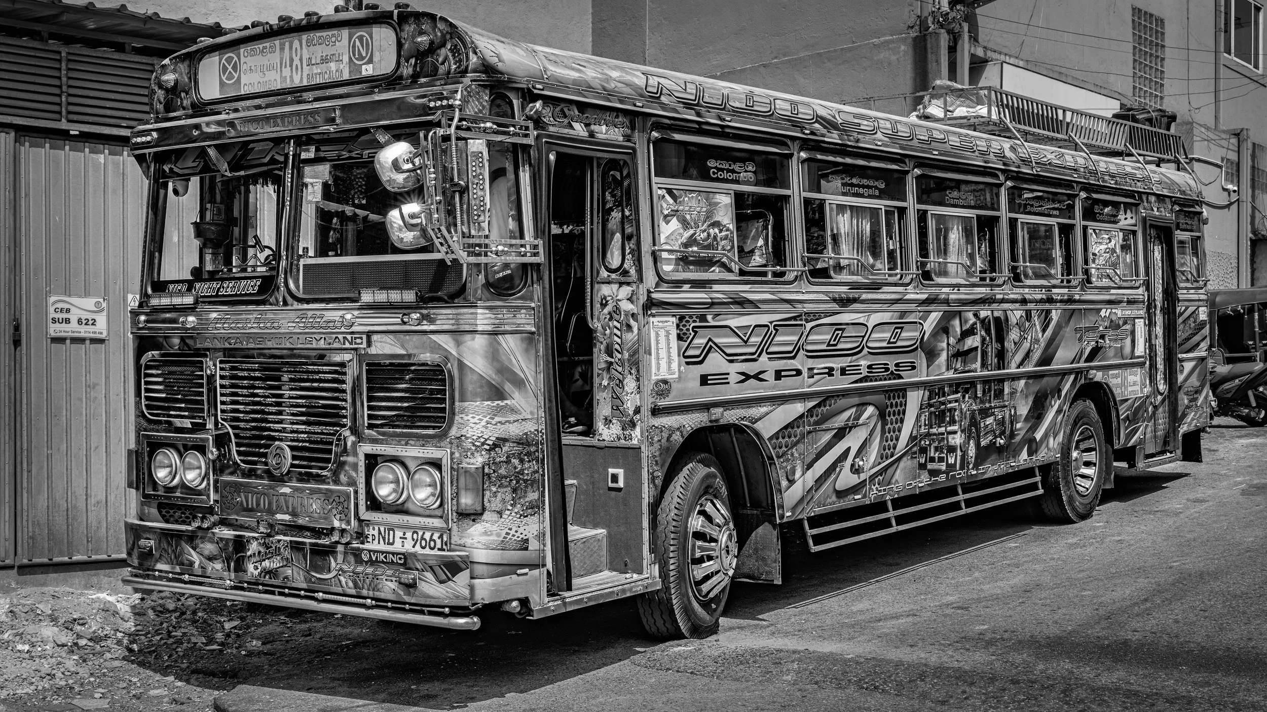 Black and white photograph of a decorated double-decker bus parked on a street, with visible signs and advertisements on its exterior.